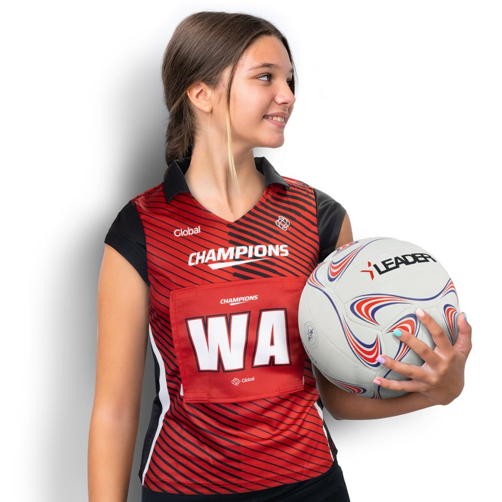 A girl wearing red printed sports wear while holding a volleyball ball with one hand.