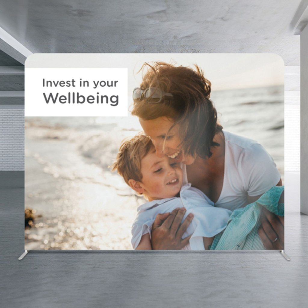 Media wall displays mother and child and 'Invest in your Wellbeing' printed, in an empty showroom.